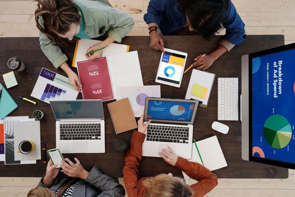 A diverse team collaborating on Market Research for Small Businesses at a desk, using laptops and tablets.